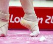 Vîrfurile îndoite ale performanţei
Nu e balerină, e gimnastă. Picioarele pline de talc cu vîrfurile îndoite şi gleznele protejate de bandaj elastic sînt ale rusoaicei Mustafina
