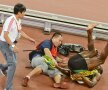 RĂSTURNAREA LUI "FULGER". Un cameraman mic dar zelos a reușit să-l doboare pe sprinterul de 1,95 m la finalul cursei de 200 m cîștigate de Bolt. (foto reuters)