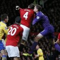 Szczesny (dreapta) rămîne cu braţul drept în aer. S-a izbit cap în cap cu Jones