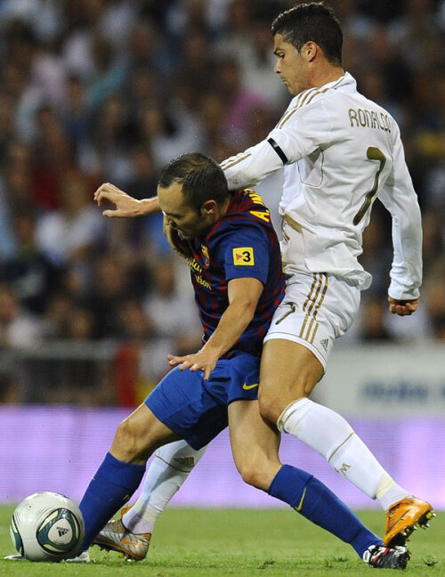 Cristiano Ronaldo (în alb) va avea iar mult de tras cu insistentul Iniesta