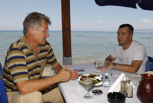 Imagine clasică pentru Grecia. Tavernă cu scaune albastre pe malul mării, tzatziki, dovlecei şi măsline pe masă. 