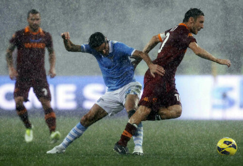 Gladiatori în ploaie. Lazialul Biava încearcă să-l deposedeze pe Totti, căpitanul Romei (dreapta) // Foto: Reuters