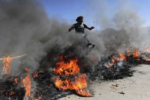 Un protestatar sare peste lanţul de cauciucuri în flăcări // Foto: Reuters