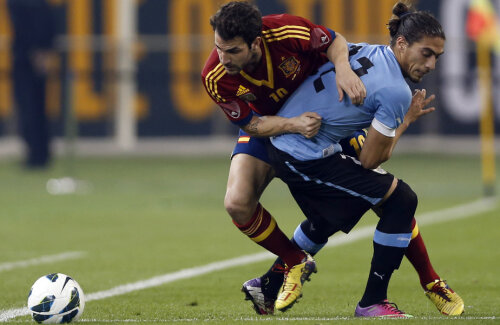 Spaniolul Fabregas, stînga, contra uruguayanului Caceres în amicalul de la Doha pentru care Villar (medalion) a încasat 3 milioane euro