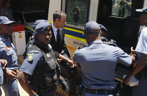 Pistorius (foto, înconjurat de polițiști) și-a împușcat letal iubita acum 2 ani, sud-africanul fiind acuzat acum de crimă cu premeditare // Foto: Reuters
