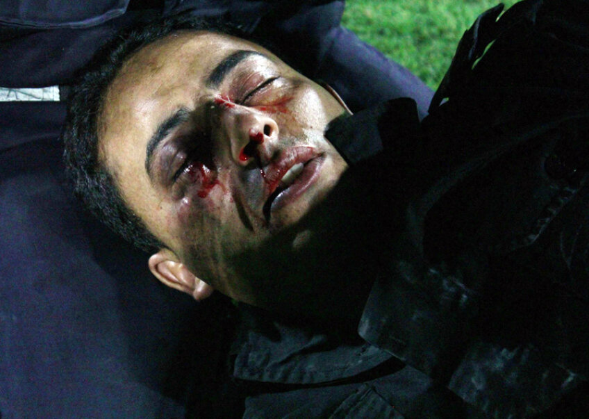 Poliţist la pămînt! SÎMBĂTĂ, SOUSSE. O victimă a furiei ultraşilor tunisieni: un poliţist leşinat, cu faţa plină de lovituri şi de sînge // Foto: Reuters