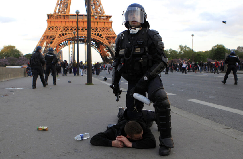 Un poliţist stă cu genunchiul pe un ultras al lui PSG // Foto: Reuters