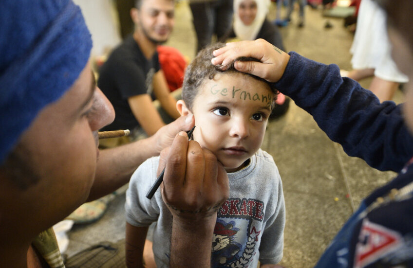 Imagine antologică: pe fruntea unui copil, părinții scriu destinația mult dorită: Germania // Foto: Raed Krishan (Budapesta)
