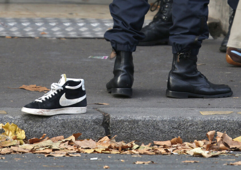 URMELE TERORII. Pe o stradă în apropiere de sala de concerte Bataclan, un pantof sport abandonat alături de ghetele poliţiştilor care au împînzit zona Foto: Reuters