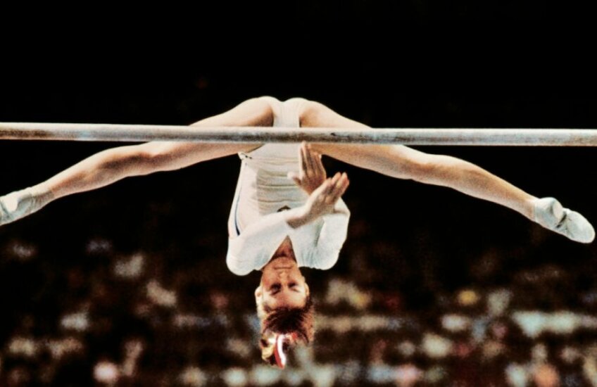 Nadia sfidează gravitația la paralele inegale, evoluând în proba pe echipe de la JO 1976 // Foto: AFP